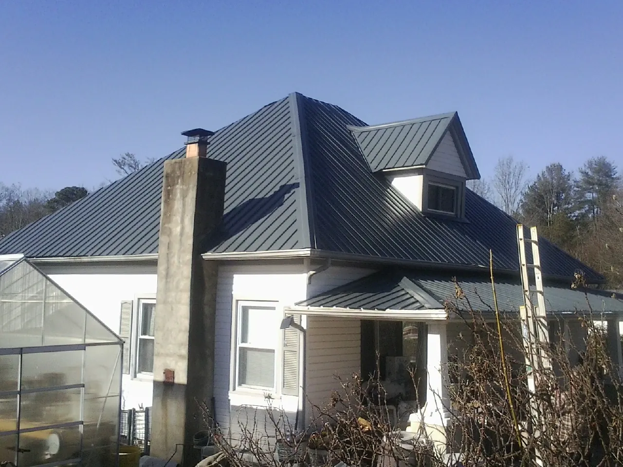 Dark blue standing seam metal roof on a white farmhouse with dormer — Slate & Tile Roof Repair by Roofing Brothers in Chesterton