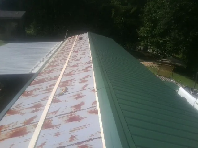 Old rusted panels beside newly installed green metal roofing — Wind Damage Roof Repair by Roofing Brothers in Chesterton