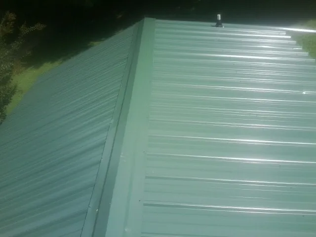 New green metal panels meeting at the ridge of a roof — Flat Roof Repair work by our crew in Chesterton