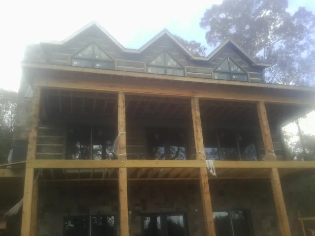 Dormers and porch framing on a large log home under construction — Roof Coating work by our crew in Chesterton