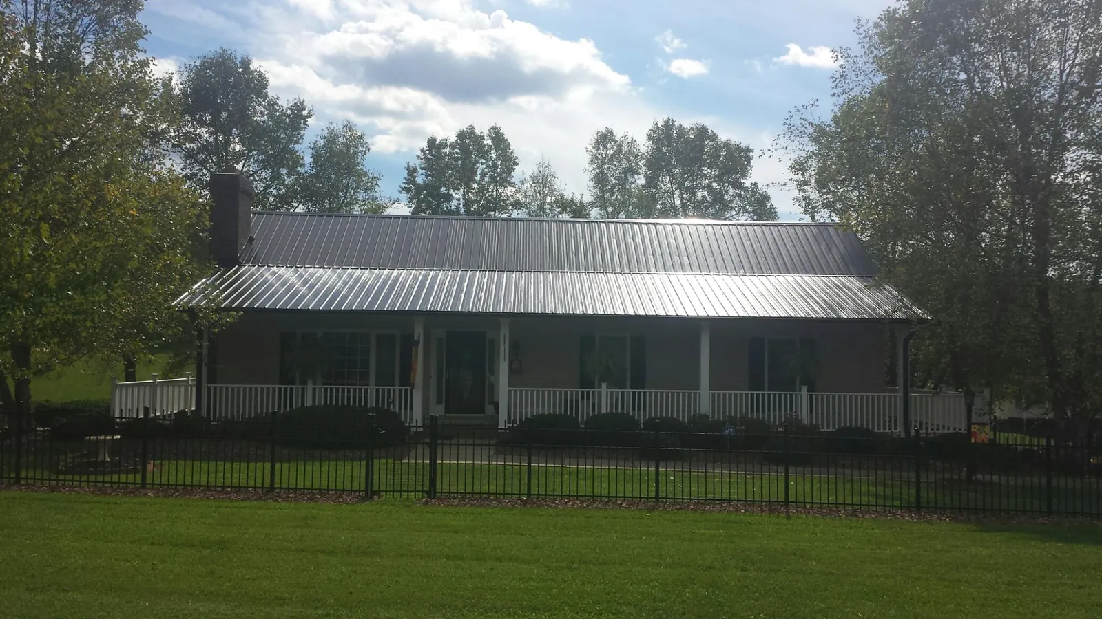 Gray metal roof on a brick ranch with a full width front porch in Chesterton