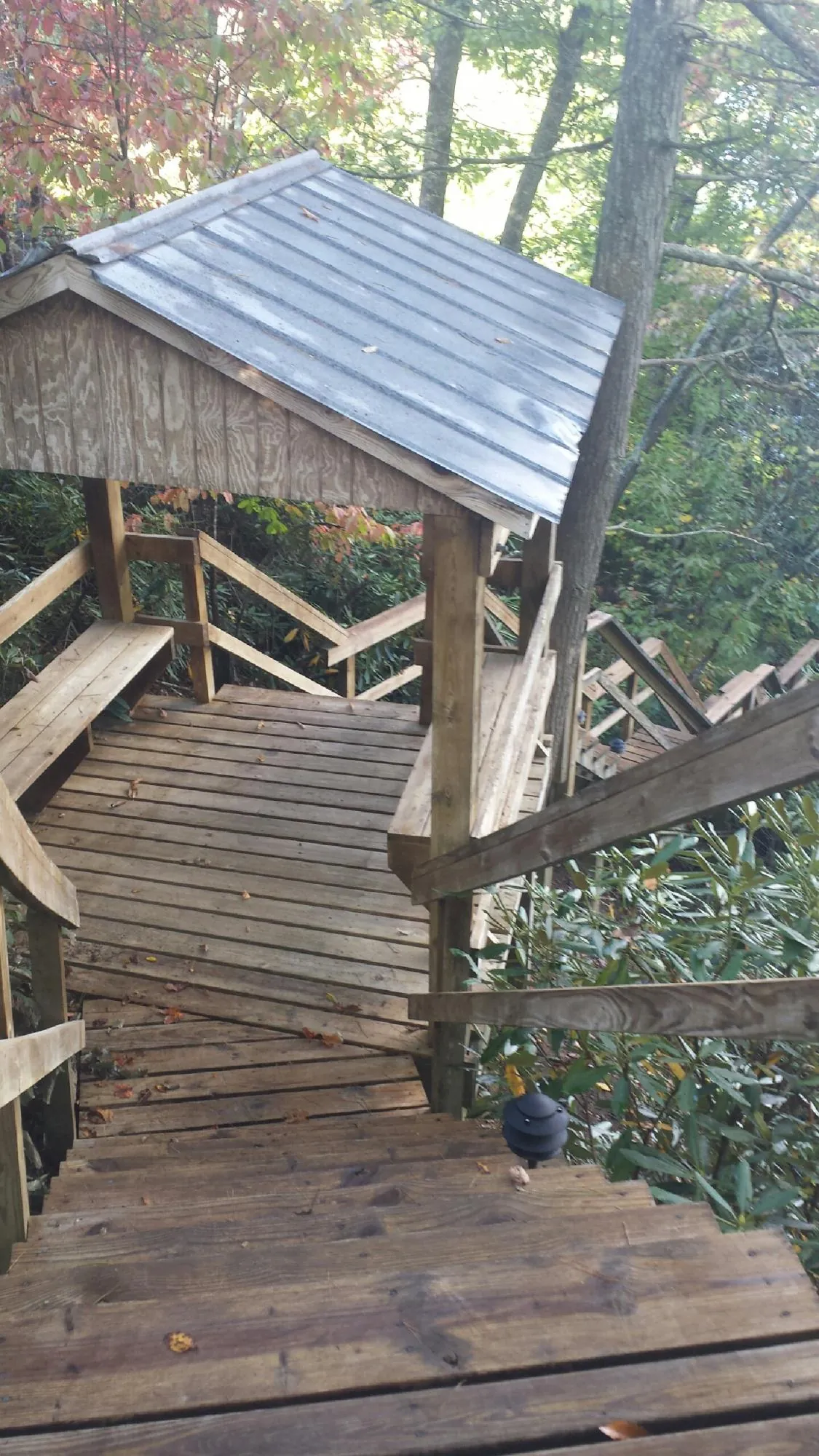 Metal roofed shelter over wooden steps on a wooded walkway — Skylight Repair & Installation work by our crew in Chesterton