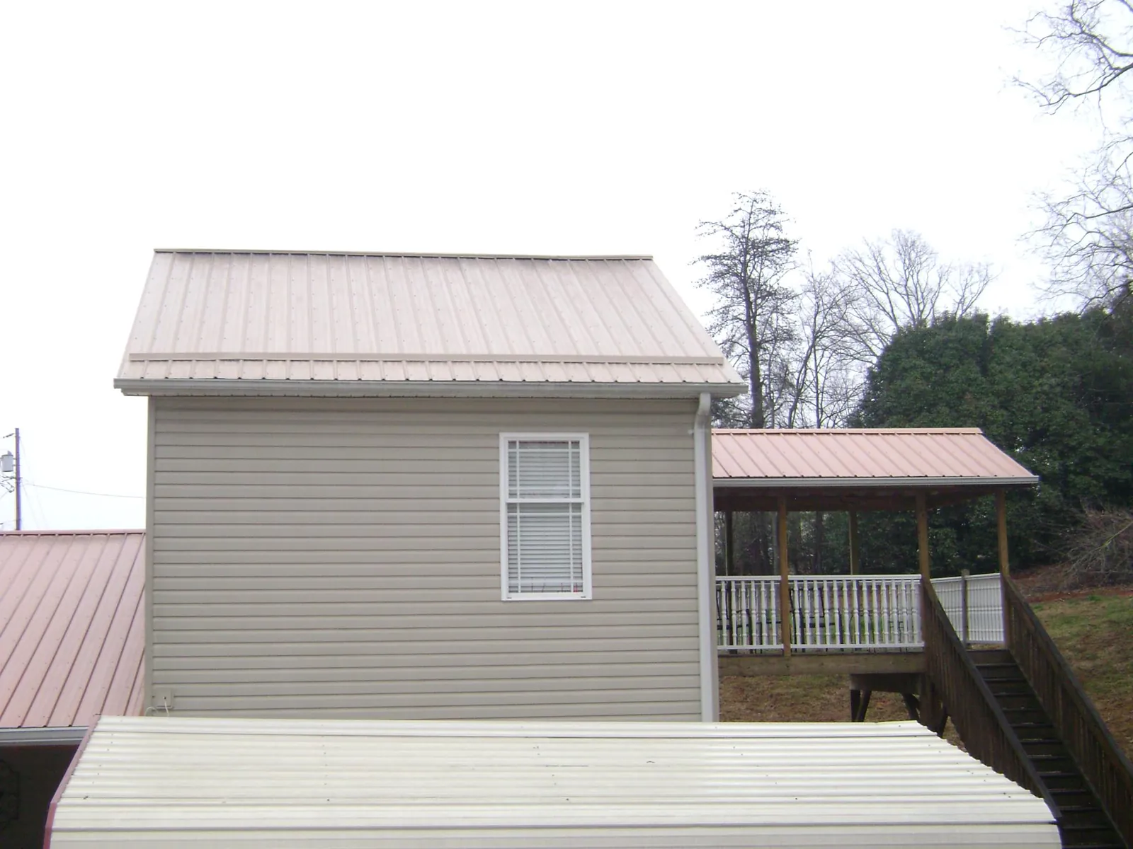 Tan metal roofs on a two story addition and attached porch, from a Roof Replacement job in Chesterton
