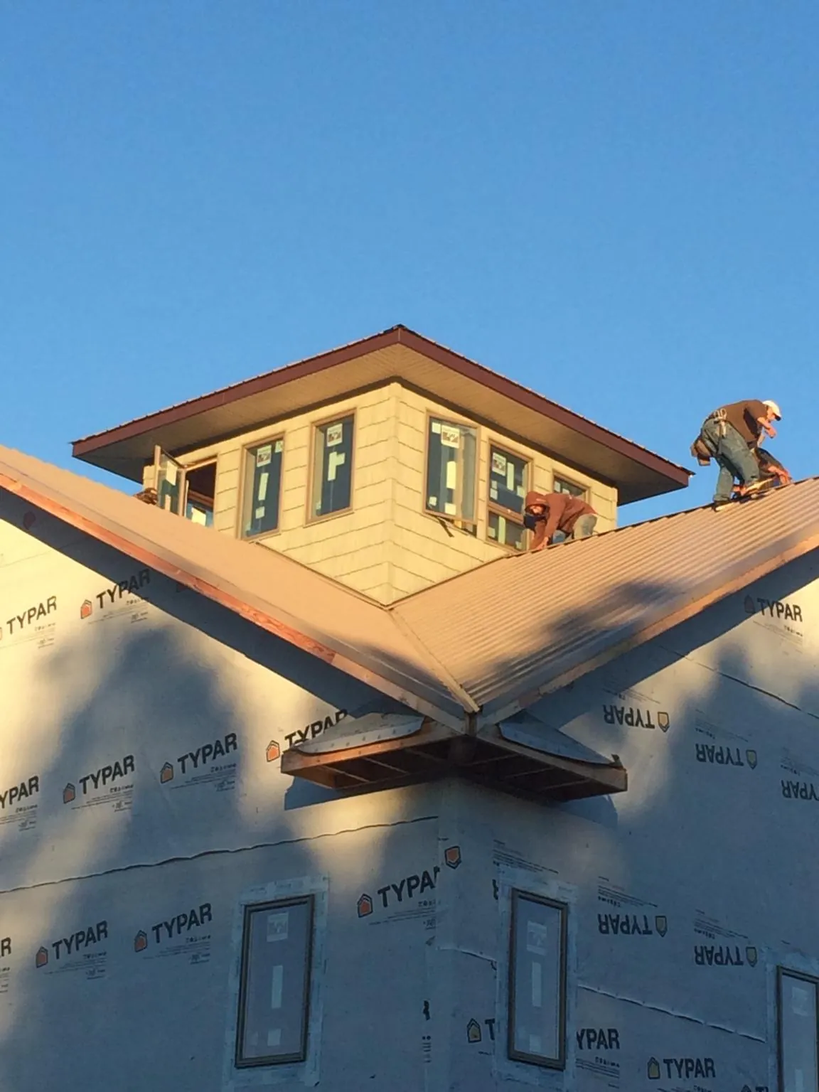 Roofers working around a rooftop cupola on a new metal roof at sunset — Roof Waterproofing in Chesterton by Roofing Brothers